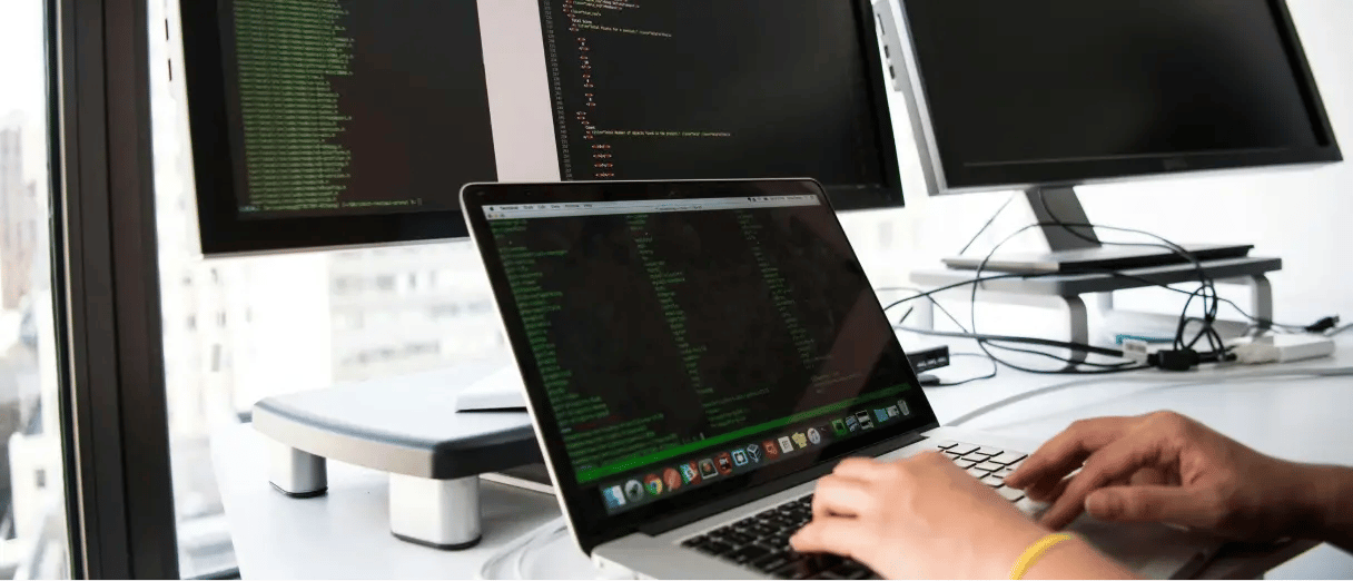 Developer working on a laptop representing hosting environments and deployment infrastructure.