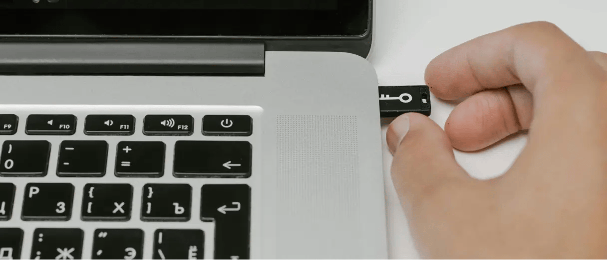 Person inserting a security key into a laptop, representing service credentials and access.
