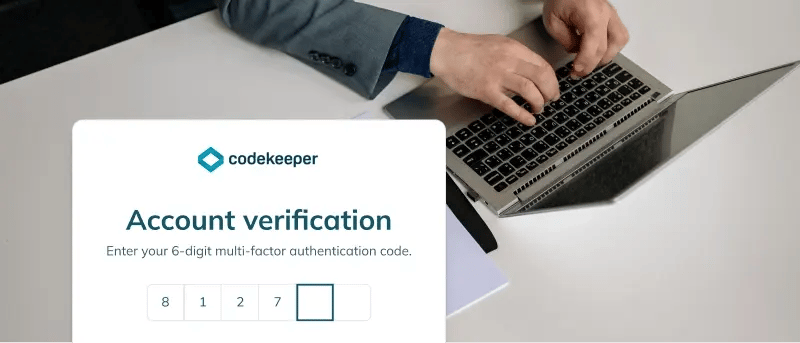 Person using a laptop with an account verification app snippet at the lower left.