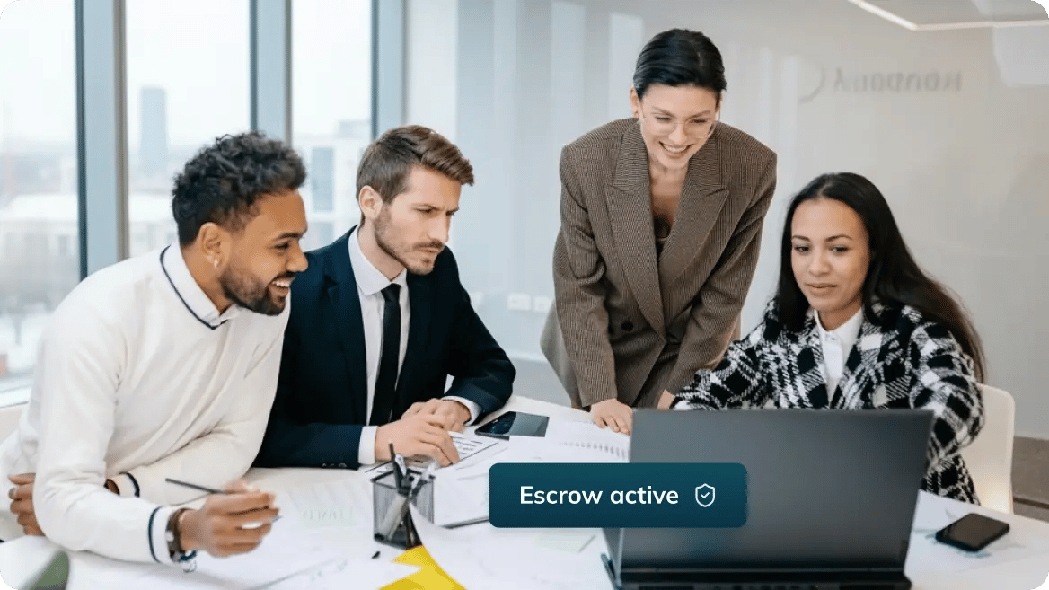 Four people in a meeting looking at a laptop together.
